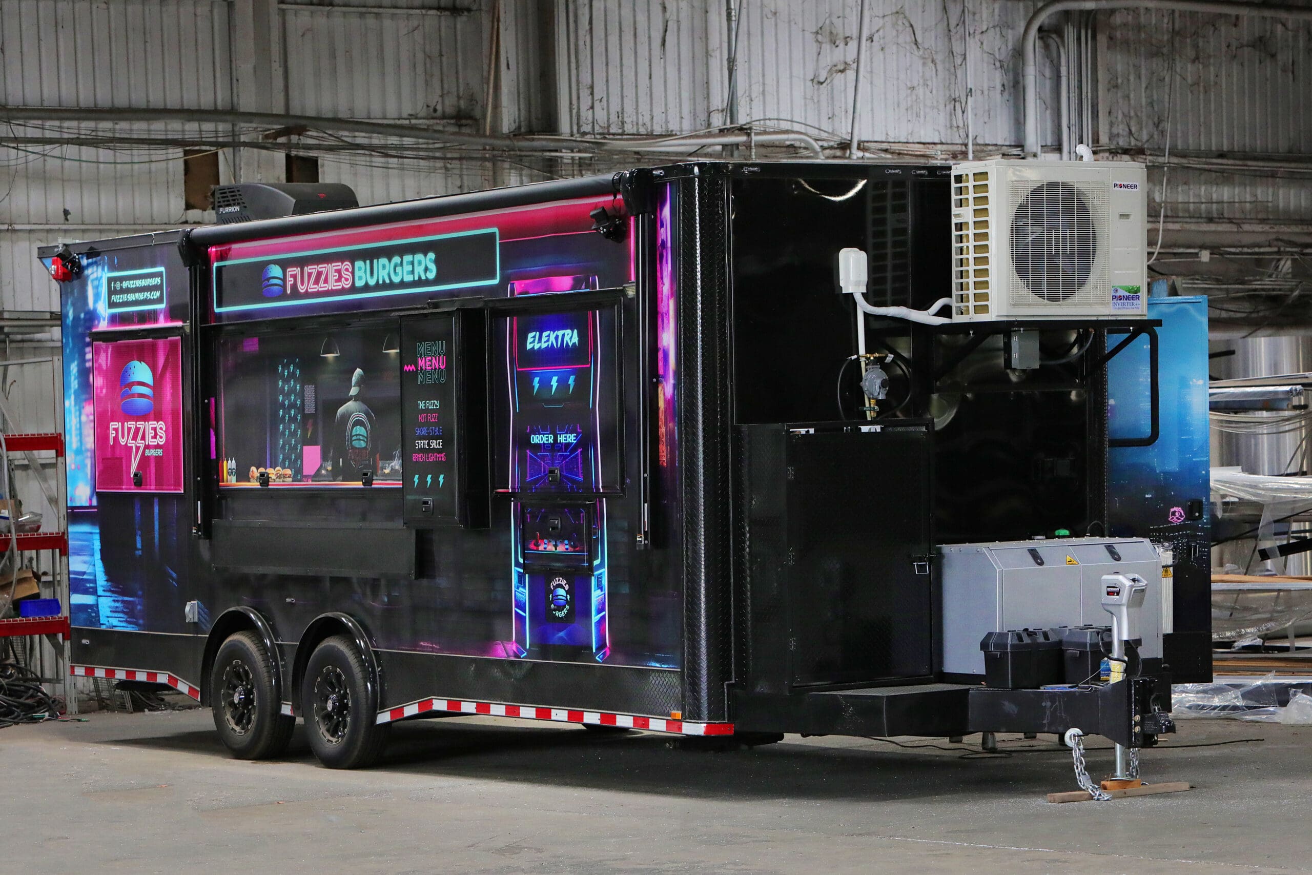 A black custom food or concession trailer with vibrant neon blue and pink lighting accents,